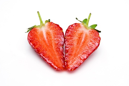 two halves of strawberries folded into a heart-shaped isolated on white background の写真素材