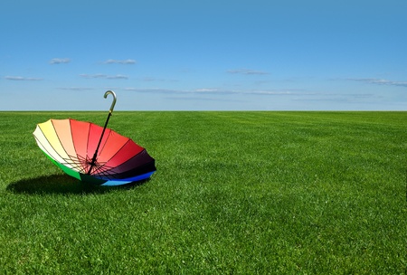 Multicolored umbrella lying on a summer meadowの写真素材