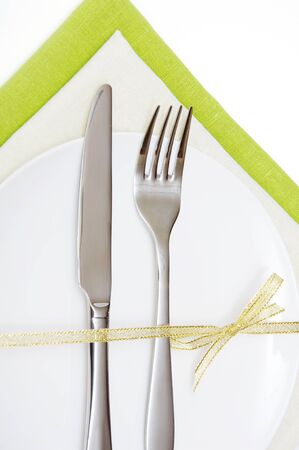 fork and knife on a white plate with a golden ribbonの写真素材