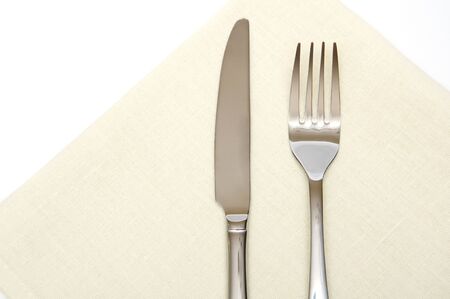 fork and knife laying on a baige napkinの写真素材