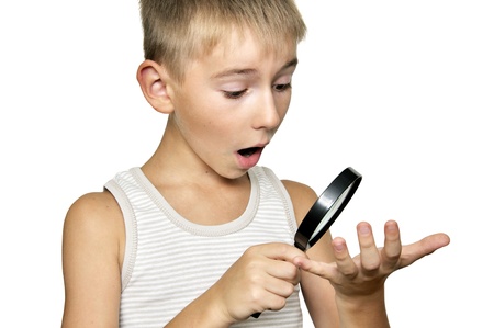 surprised boy looking through a magnifying glass isolated on a white backgroundの写真素材