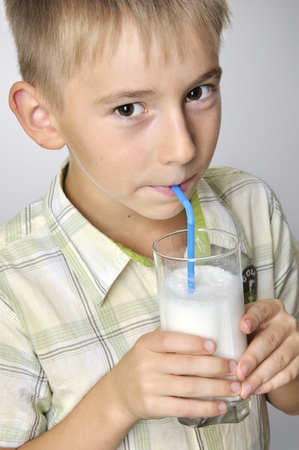 portrait of smiling boy drinking strawberry milkshake close-upの写真素材