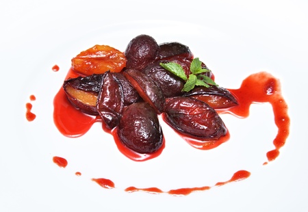 sliced plum baked in caramel on white plateの写真素材