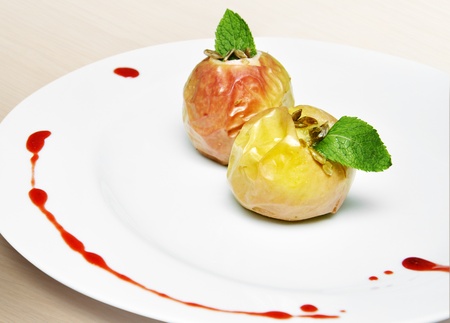 Baked apple with honey and sunflower seeds on a white plateの写真素材