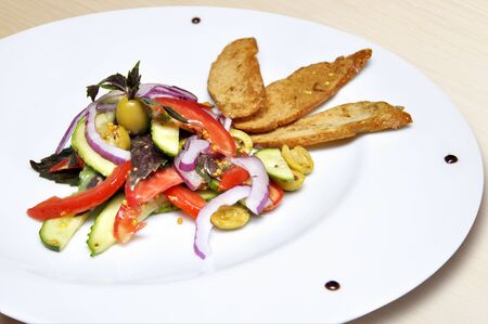 diet salad with tomato, cucumber, onion, olives and croutons on a white plateの写真素材