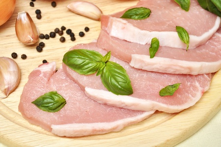 raw meat on a cutting board with pepper, basil and garlicの写真素材