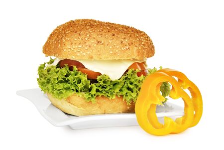 Big vegetarian sandwich with lettuce, tomato, sweet pepper and cheese on white plate isolated on white backgroundの写真素材