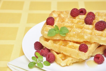 Waffles with honey and raspberry on white plateの写真素材