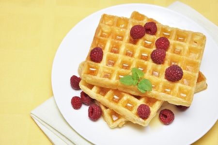 Waffles with honey and raspberry on white plateの写真素材