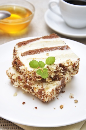 Sweet dessert. Two slices of cake on white plate with cup of coffe and honeyの写真素材