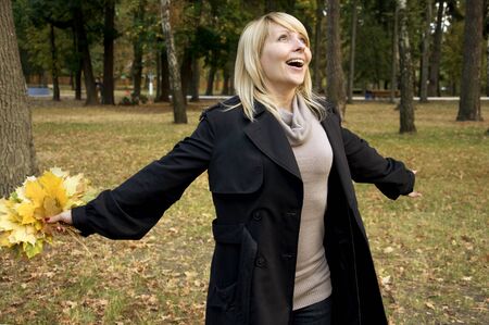 happy beautiful woman with maple leaves in her hands in autumn parkの写真素材