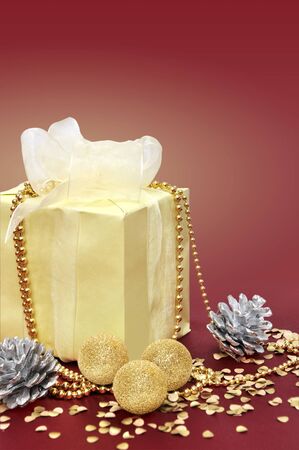 Yellow gift box with light ribbon and Christmas decorations on purple  backgroundの写真素材