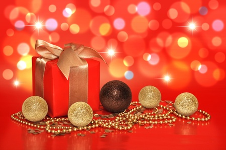 Red gift box with golden ribbon and cristmas decoration on red backgroundの写真素材