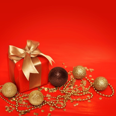 Red gift box with golden ribbon and cristmas decoration on red background with copy spaceの写真素材