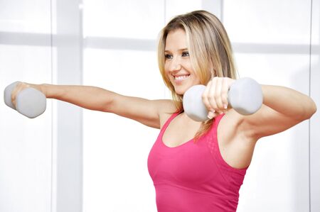 Pretty happy young woman exercising with free weightsの写真素材