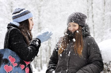 Two girls plays with snow at winter parkの写真素材