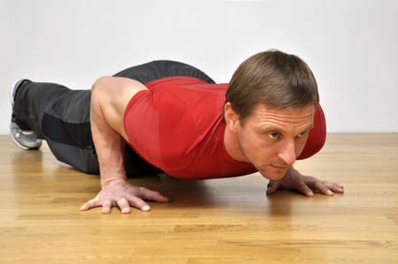 Handsome fit man pursuing a healthy lifestyle, doing pushup fitness exercise in the gymの写真素材