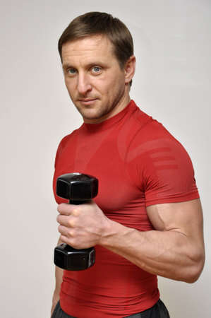 Athletic man  with a dumbells over light backgroundの写真素材