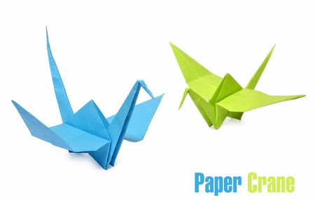 Traditional Japanese origami cranes made from blue and green paper over white backgroundの写真素材