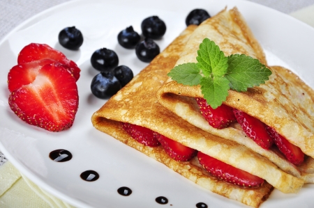 Pancakes sereved with strawberries and blueberries on plateの写真素材