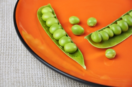 fresh green peas on a orange plate close upの写真素材