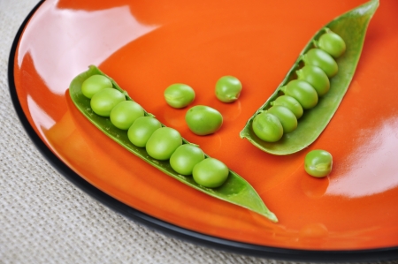 fresh green peas on a orange plate close upの写真素材