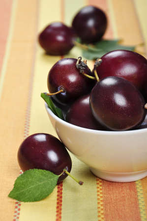 Fresh ripe plums in white bowl. Selective focus, shallow dofの写真素材