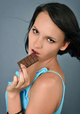passionate woman with chocolate over grey backgroundの写真素材