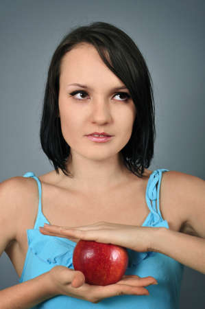 Pretty young woman with red apple in her handsの写真素材