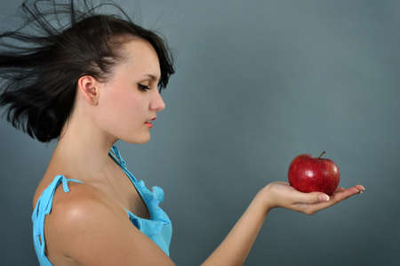 Pretty young woman with red apple in her handsの写真素材