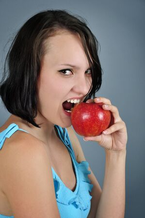 Pretty young woman eating red appleの写真素材