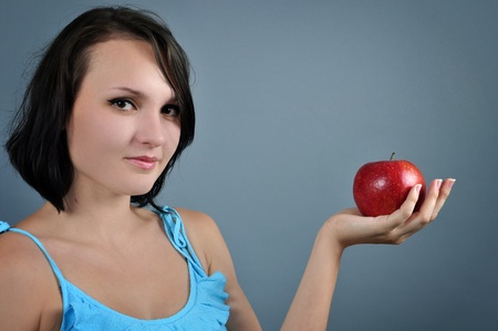 Portrait of an attractive young woman with red apple in her handの写真素材