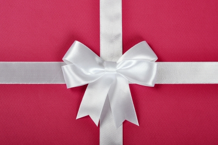 White ribbon with bow on a pink backgroundの写真素材
