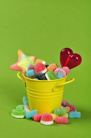 Colorful candies in yellow bucket on green backgroundの写真素材