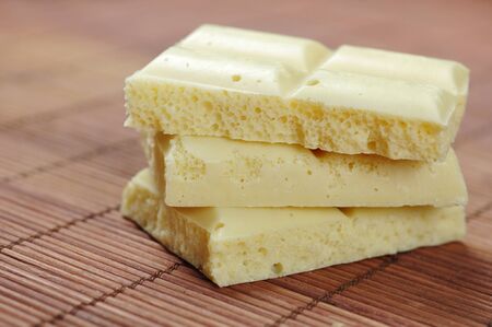 White porous chocolate pieces on a bamboo place-mat closeup. Small shallow DOF.の写真素材