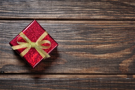 Red gift box with golden ribbon on wooden backgroundの写真素材