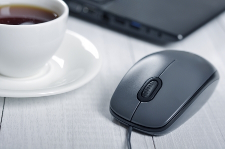 mouse and laptop with cup of coffee on the table closeupの写真素材