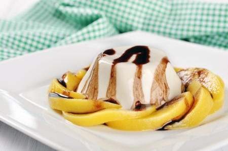 Italian dessert Panna cotta with peach and chocolate sauce on the plateの写真素材