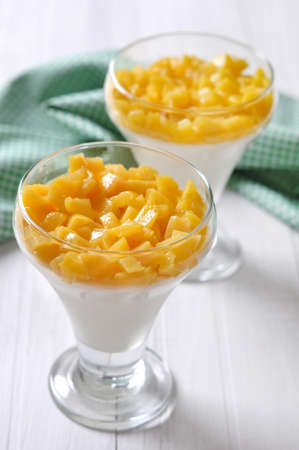 Dessert with peach in a glass on white backgroundの写真素材