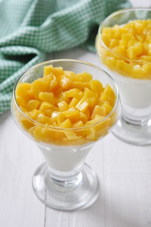 Dessert with peach in a glass on wooden backgroundの写真素材