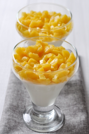 Italian dessert Panna cotta with peach in glassesの写真素材