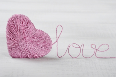 Two pink clews in shape of heart on white wooden backgroundの写真素材