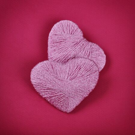 Two pink clews in shape of heart on red background
の写真素材