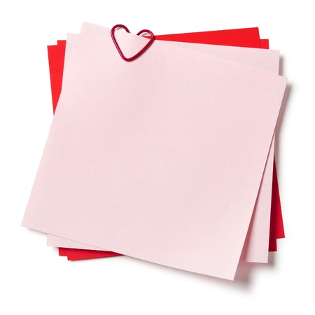 pink and red sticky notes with paper clip in shape of heart on white backgroundの写真素材