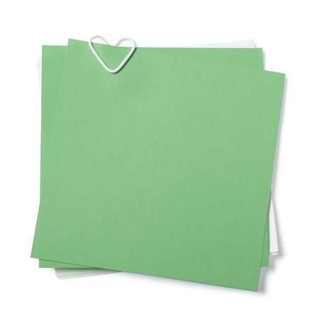 green and white sticky notes with paper clip in shape of heart on white backgroundの写真素材
