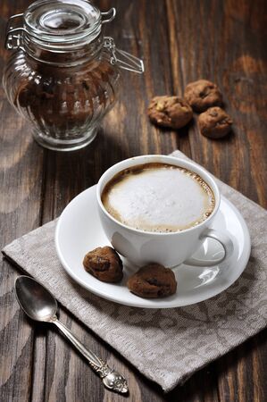 Cup of coffee with cookies over wooden backgroundの写真素材