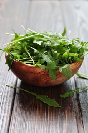 Fresh arugula leaves in wooden bowl on a wooden backgroundの写真素材