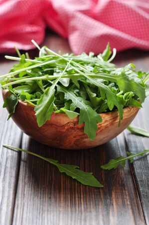 Fresh arugula leaves in wooden bowl on a wooden backgroundの写真素材
