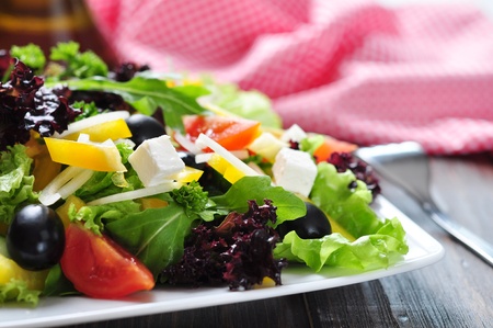 Greek salad on white plate on wooden background closeupの写真素材