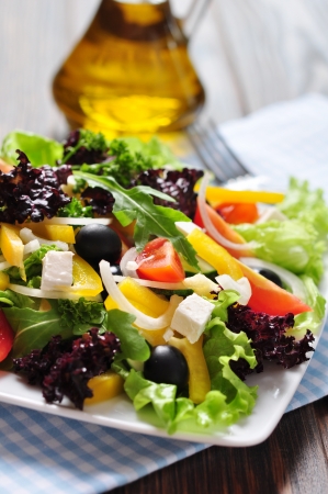Greek salad on white plate on wooden background closeupの写真素材